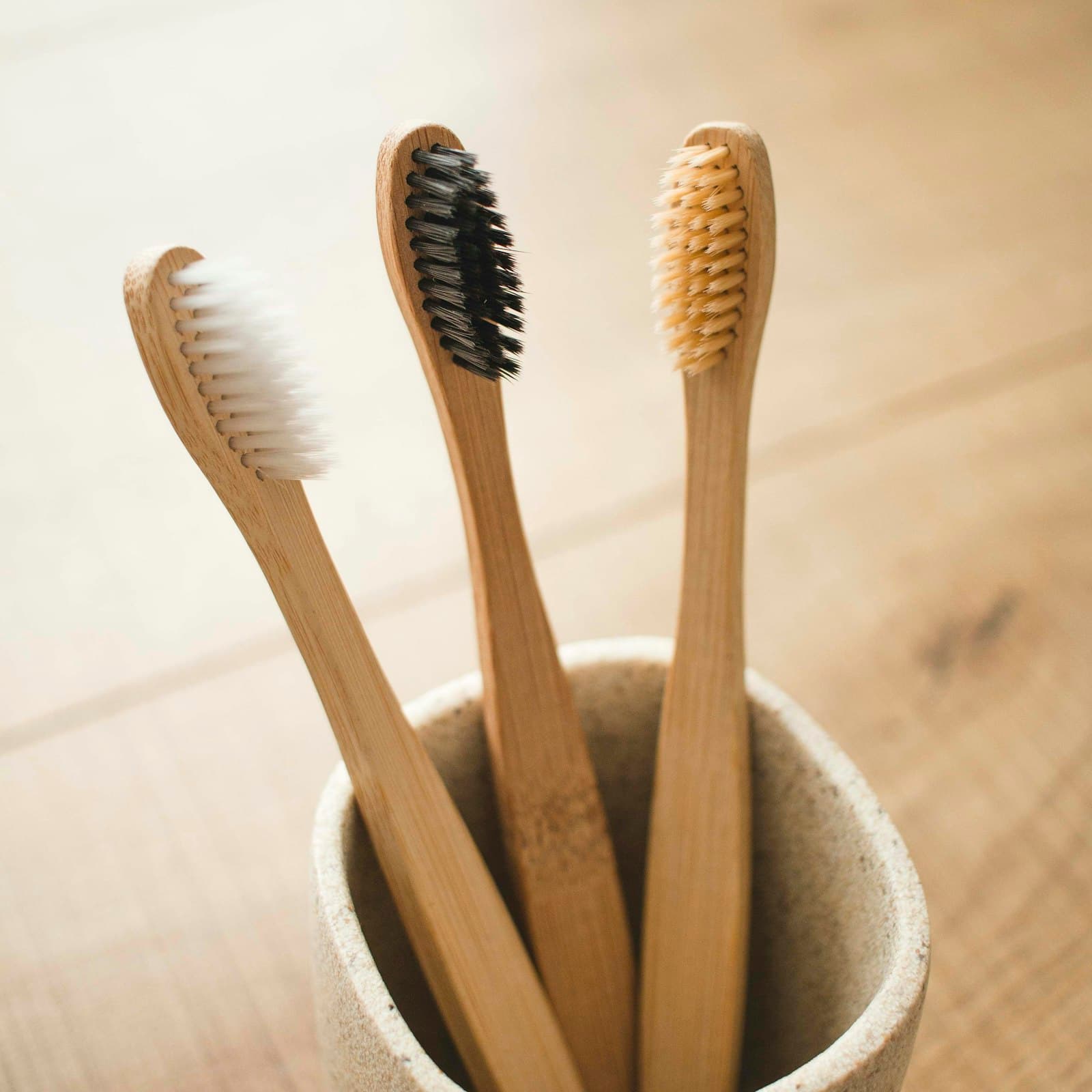 Three bamboo toothbrushes standing in a ceramic cup
